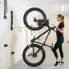 Woman rolling a fat tyre bicycle into a Steadyrack wall-mounted bike rack in a garage.
