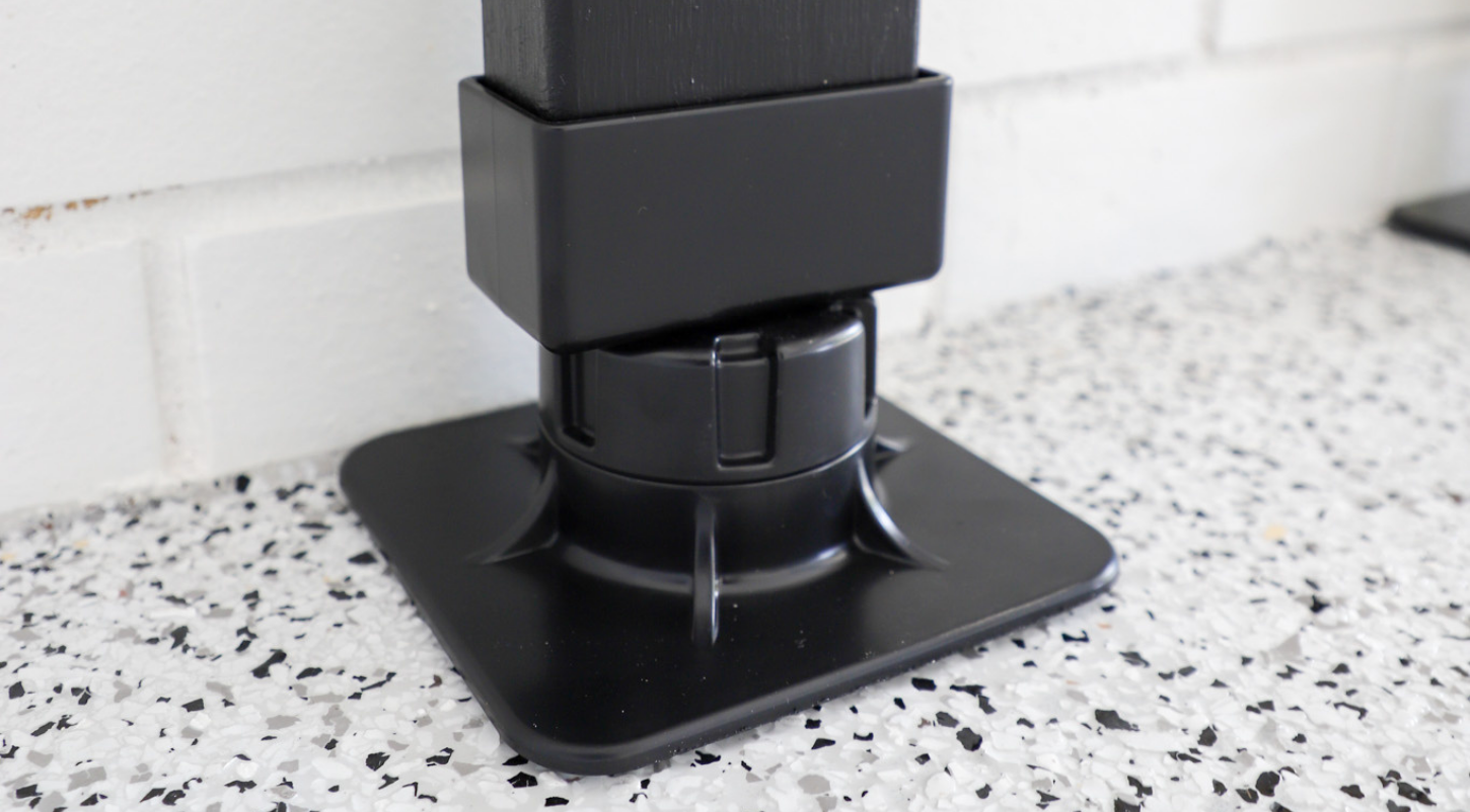 Black plastic base on speckled flooring with white brick wall background