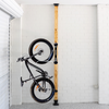 Bicycle mounted against a wooden post with white brick walls.