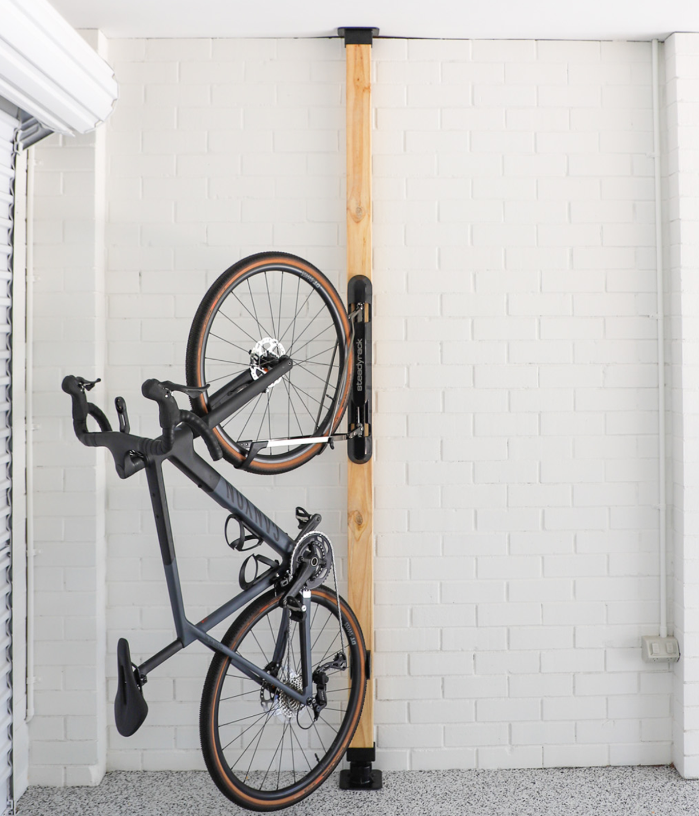 Bicycle mounted on a vertical bike rack against a white tiled wall.