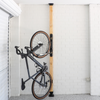 Bicycle mounted on a wall rack against a white tiled wall.