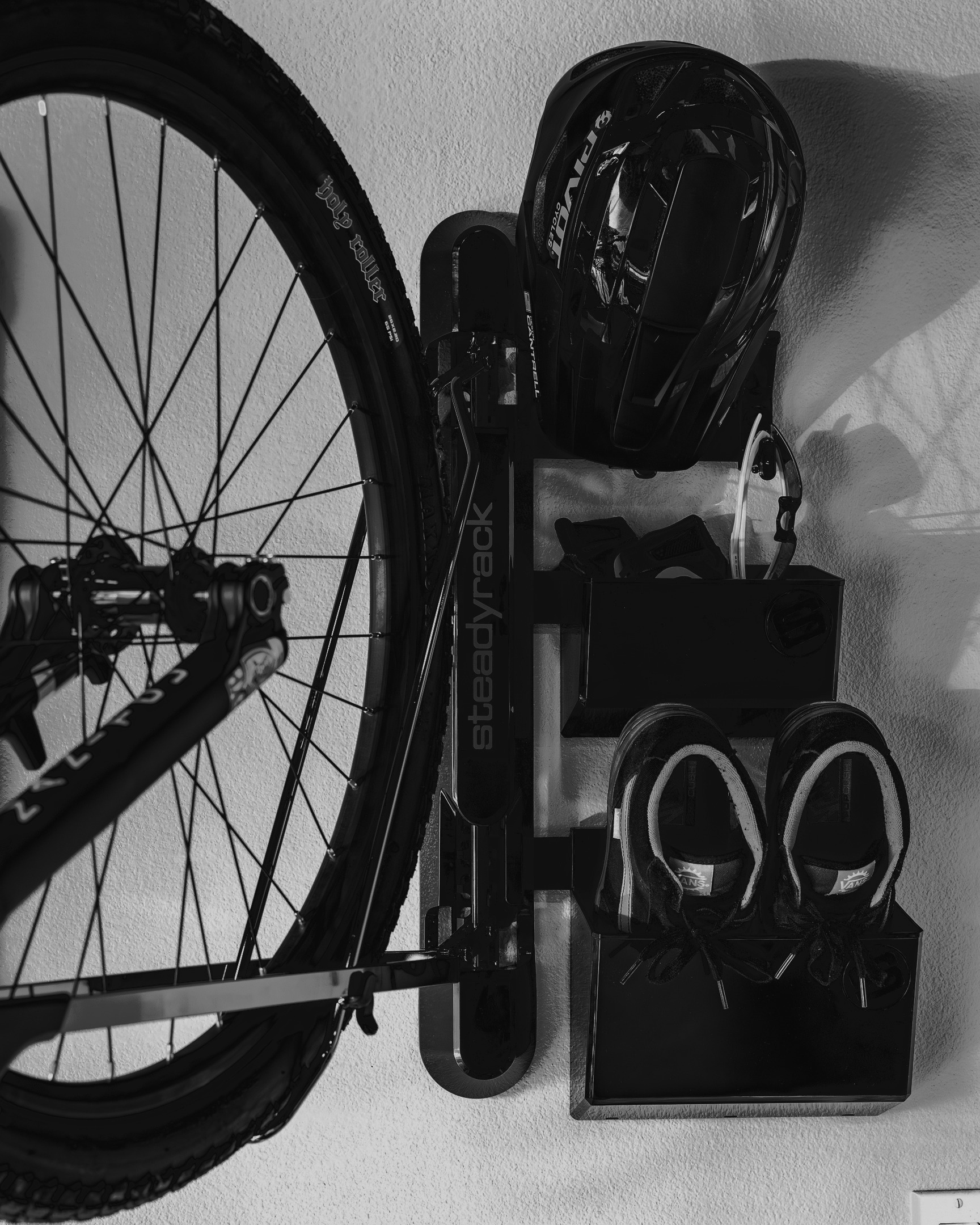 Bicycle leaning against a wall with shoes and a helmet on a holder.